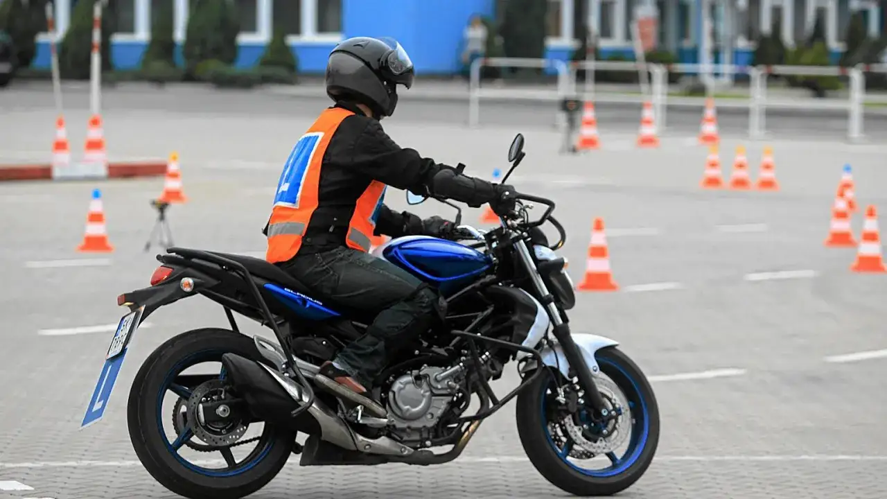 Osoba w kamizelce odblaskowej i kasku jeździ na motocyklu po placu manewrowym. Zastanawiasz się, ile kosztuje prawo jazdy na motor?