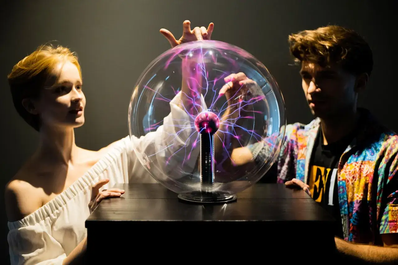 Dzieci w muzeum we Wrocławiu odkrywają tajemnice elektryczności, dotykając kuli plazmowej.