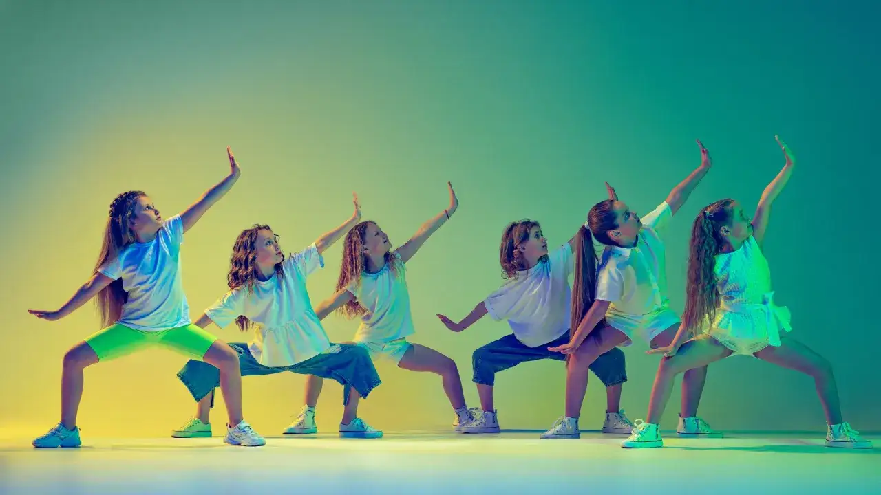 Dziewczynki w ruchu, pokazujące, jak nie być sztywnym w tańcu. Ich dynamiczne pozy i swobodne gesty emanują energią.