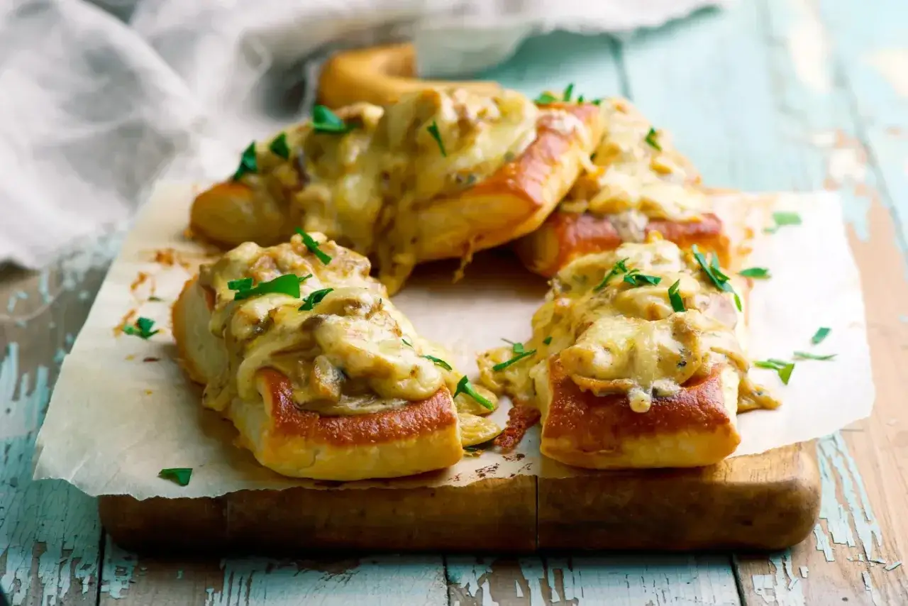 Pyszne zapiekanki z bagietki z kremowym farszem grzybowym i ciągnącym się serem, posypane natką pietruszki.