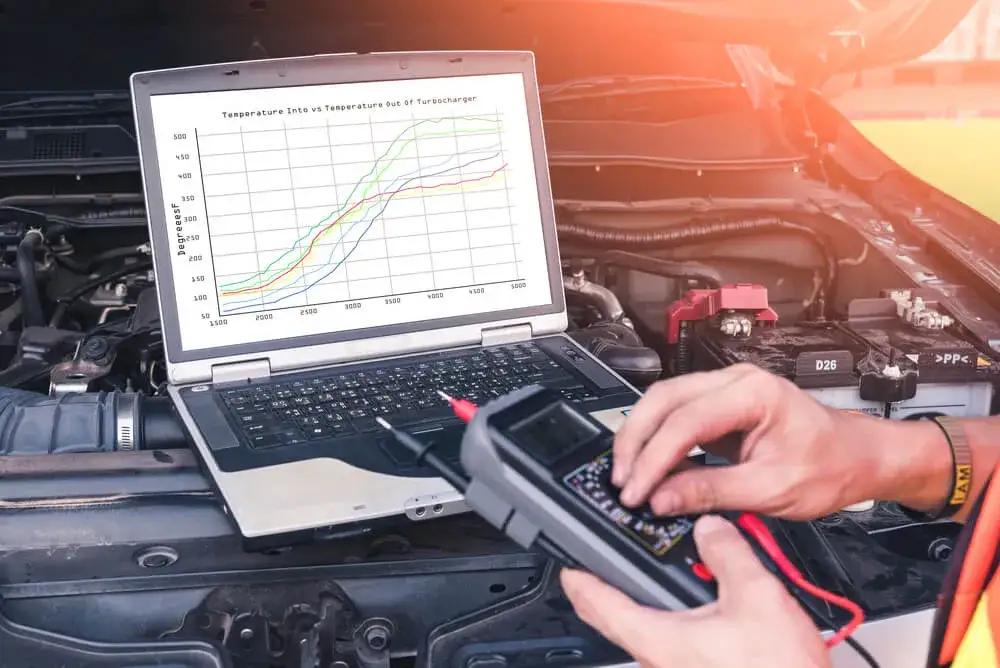 mechanik podłącza komputer diagnostyczny do samochodu