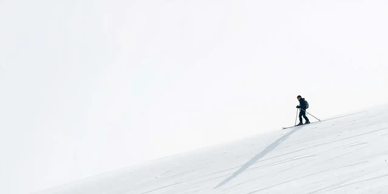 Narciarz na stoku, cień rzucany przez niego podkreśla, jak zabezpieczyć kolana na nartach, dbając o bezpieczeństwo.