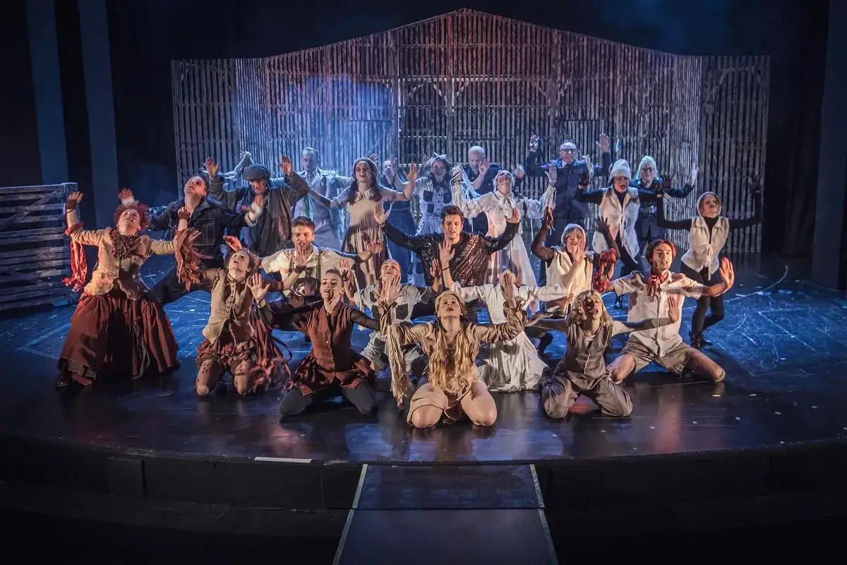 Aktorzy na scenie, w strojach z epoki, z rękami w górze. To scena z przedstawienia, które mogłoby być uznane za najlepszy teatr w Polsce.