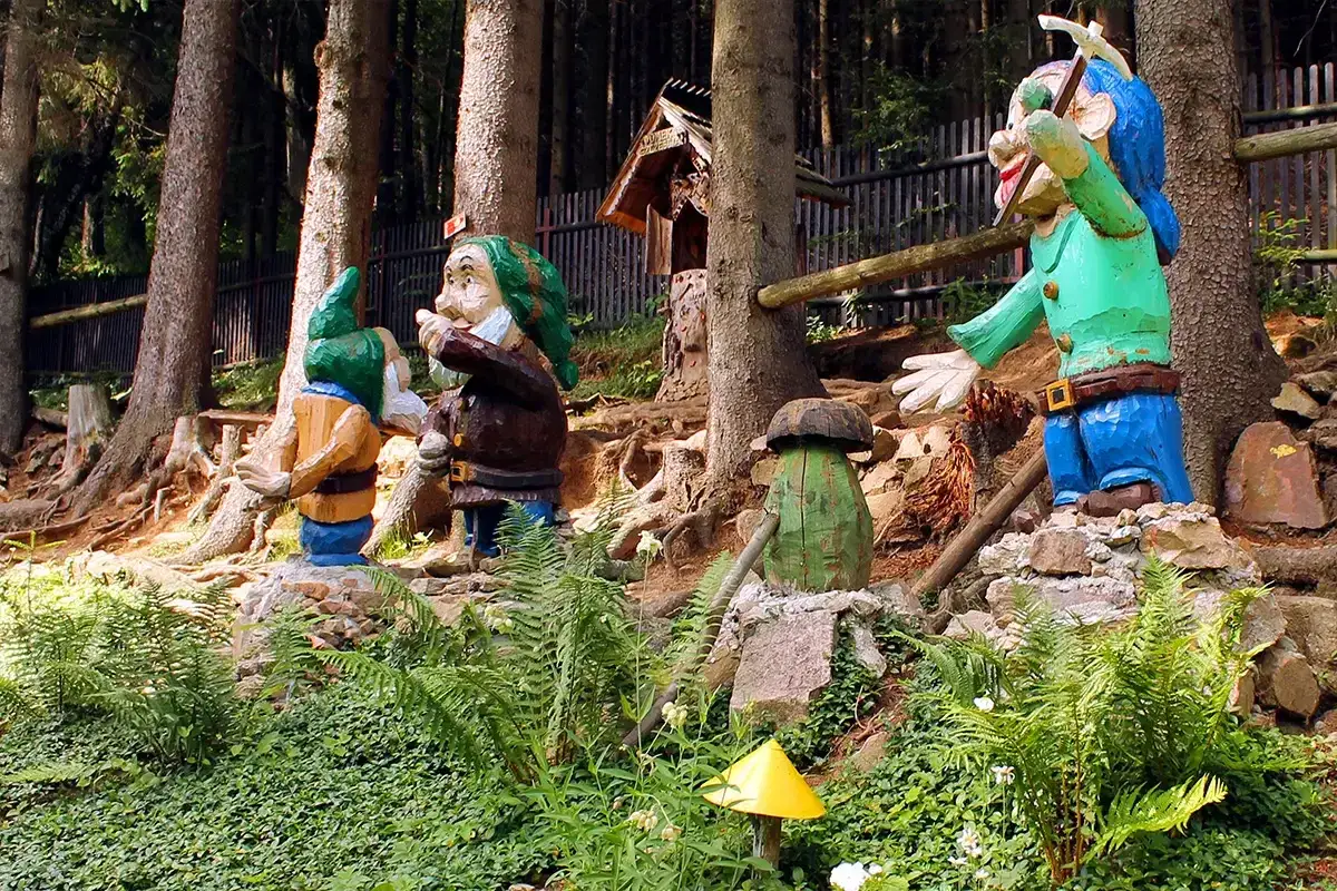 Kolorowe figurki krasnali i grzyb&oacute;w w lesie tworzą magiczny ogr&oacute;d bajek w Międzyg&oacute;rzu.
