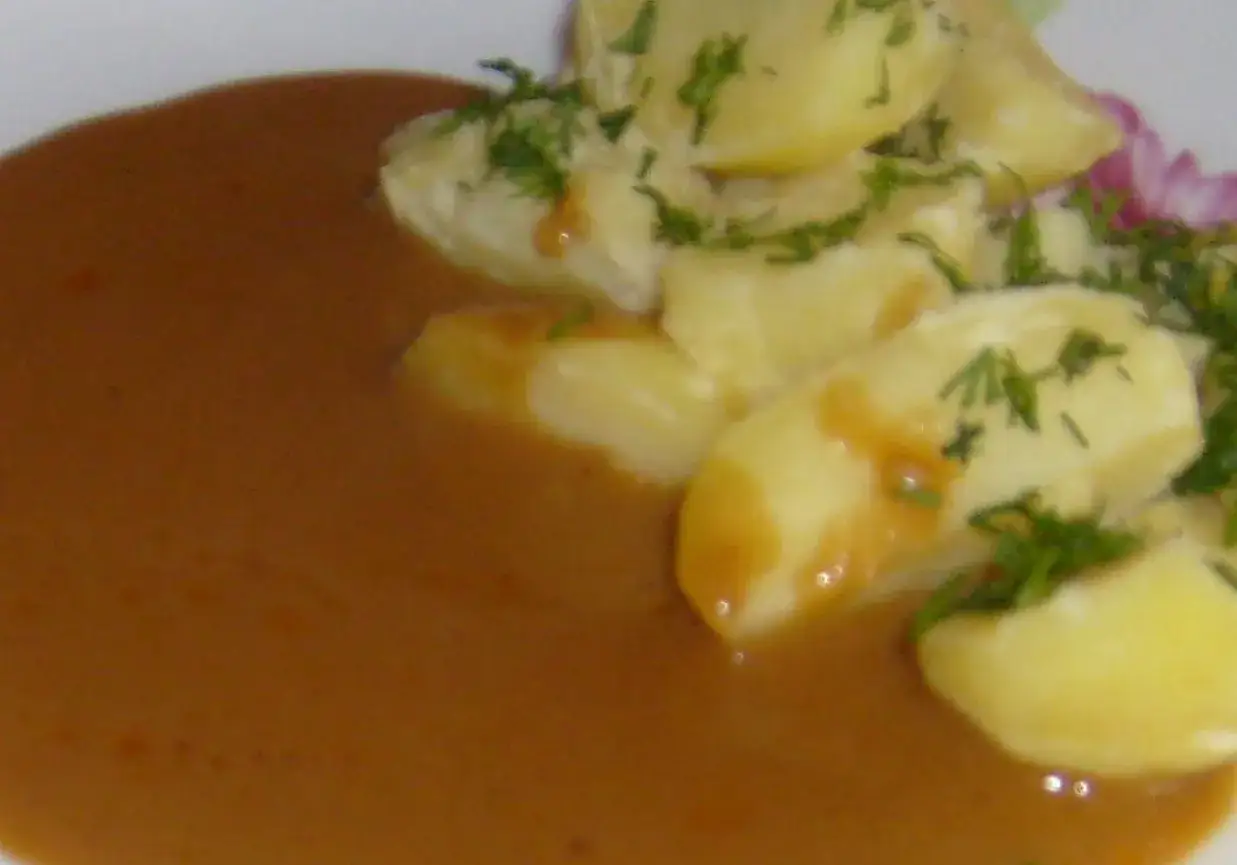 Ziemniaki w sosie pieczeniowym, posypane zielonym koperkiem. Pyszne danie obiadowe.