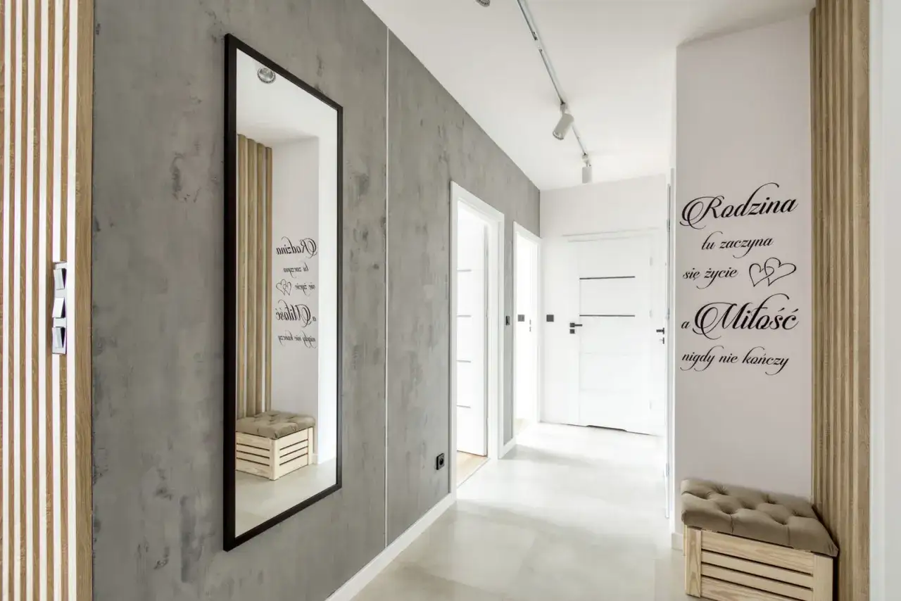 Nowoczesny przedpok&oacute;j z betonową ścianą, lustrem i napisem 
