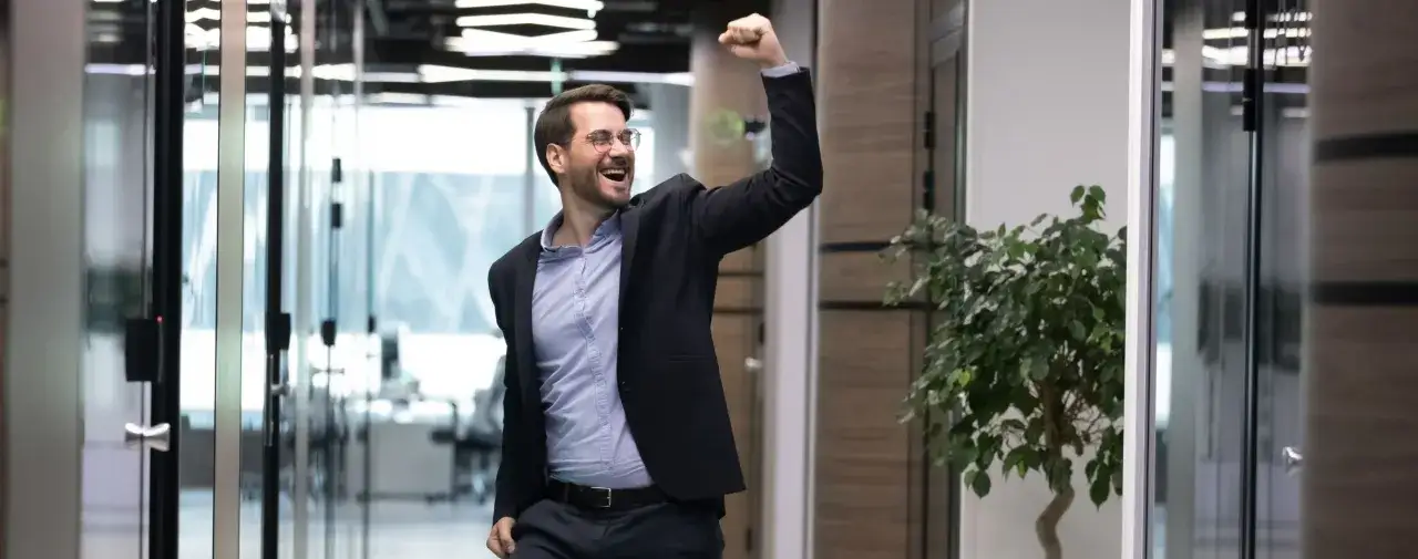 Szczęśliwy mężczyzna w garniturze świętuje sukces, być może po złożeniu wniosku o awans stanowiskowy.