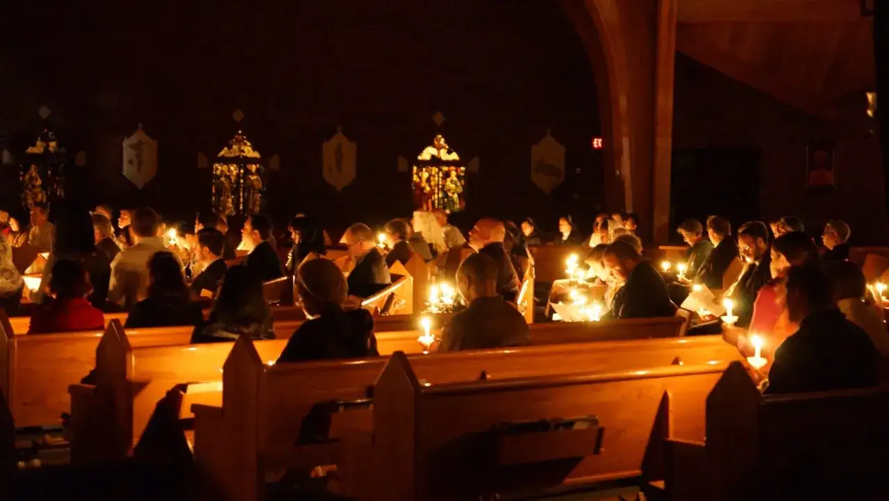 Ludzie siedzą w kościele przy świecach, gdy kończą się roraty.