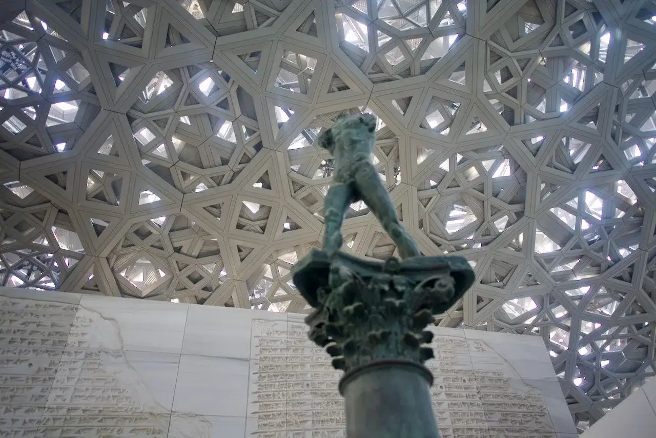 Posąg w Luwr Abu Zabi pod geometryczną kopułą.