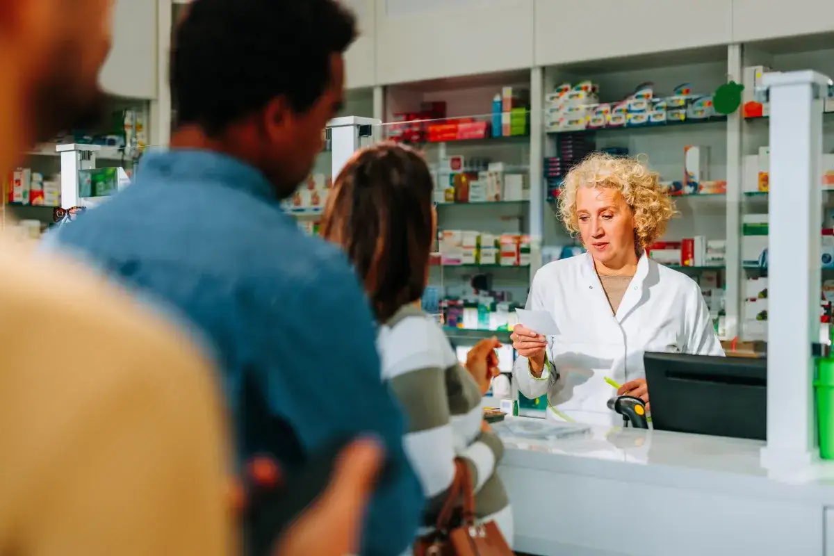 Farmaceutka wyjaśnia, jak dostać leki na depresję, czytając receptę. W tle p&oacute;łki z lekami.