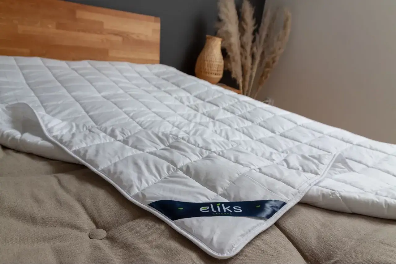 Biała, pikowana kołdra obciążeniowa na łóżku. Dowiedz się, jak dobrać idealną kołdrę obciążeniową dla siebie.