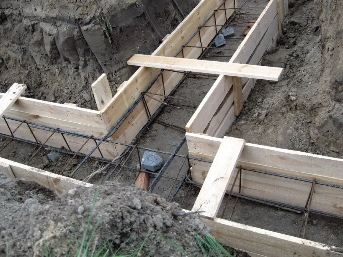 Wykop pod ławy fundamentowe z zbrojeniem i szalunkiem z desek. Budowa trwa.
