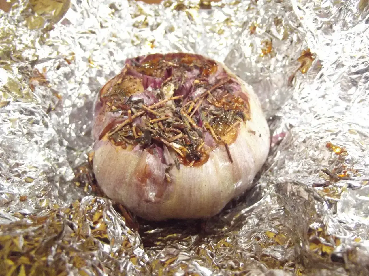 Aromatyczny czosnek z grilla, zapieczony w folii aluminiowej z ziołami.