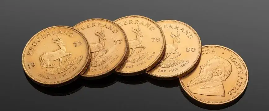 Złote sztabki i monety bulionowe obok siebie