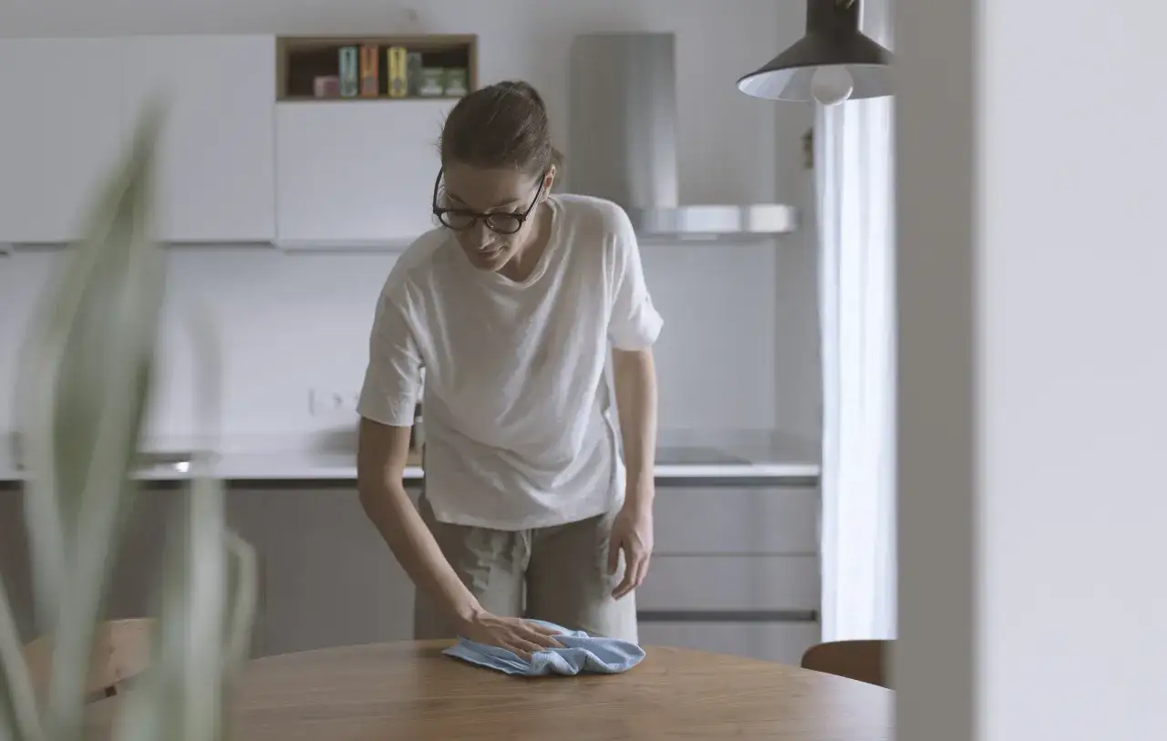 Kobieta w okularach sprząta st&oacute;ł, ćwicząc sztukę wyrzucania rzeczy.