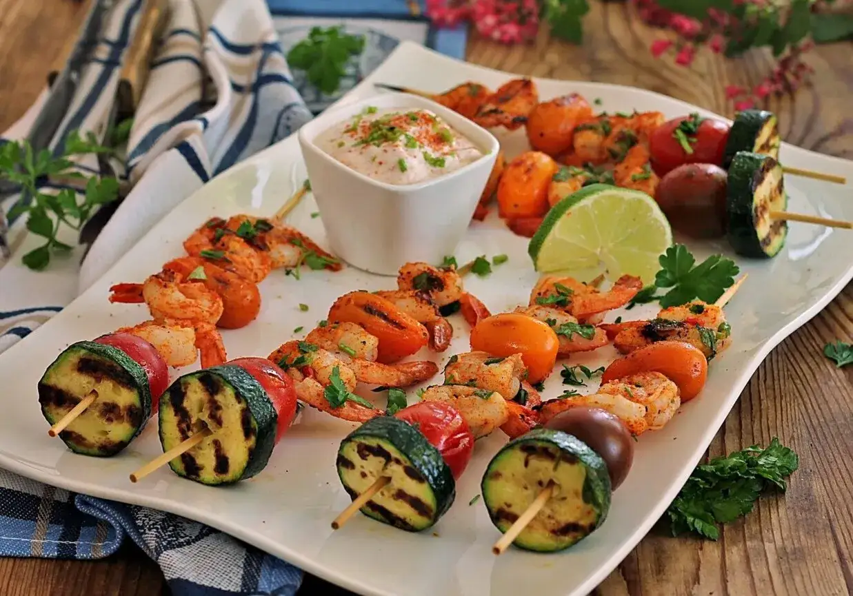 Pyszne krewetki z grilla z pomidorkami i cukinią, podane z dipem i limonką. Idealne na letnie przyjęcie.