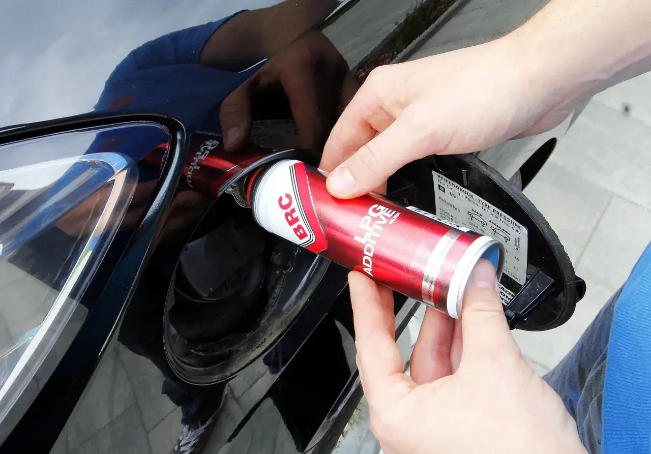 Ręce wlewają dodatek do paliwa LPG, dbając o czyszczenie wtrysków lpg.