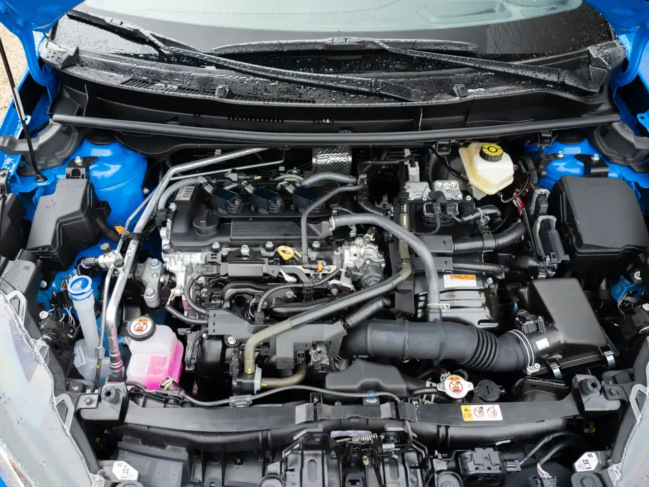 Silnik Toyoty Yaris pod maską: widok na jednostkę napędową, przewody, płyny i elementy układu dolotowego.