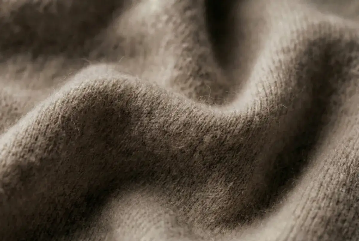 Miękki, beżowy kaszmir w zbliżeniu. Delikatne włókna sugerują, jak prać szalik z kaszmiru, by zachował swoją miękkość.