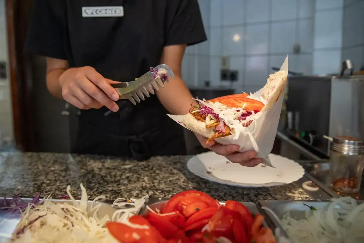 Ręce przygotowują świeżego kebaba z warzywami. Zastanawiasz się, ile kosztuje kebab w Niemczech?