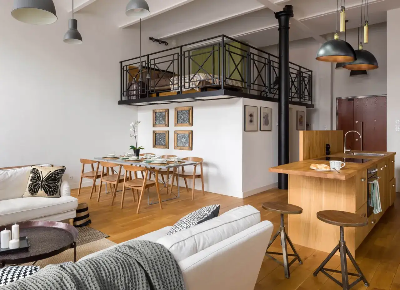 Nowoczesna antresola co to? To podwyższona przestrzeń sypialna nad salonem, z metalową balustradą, widoczna nad stołem i kuchnią.