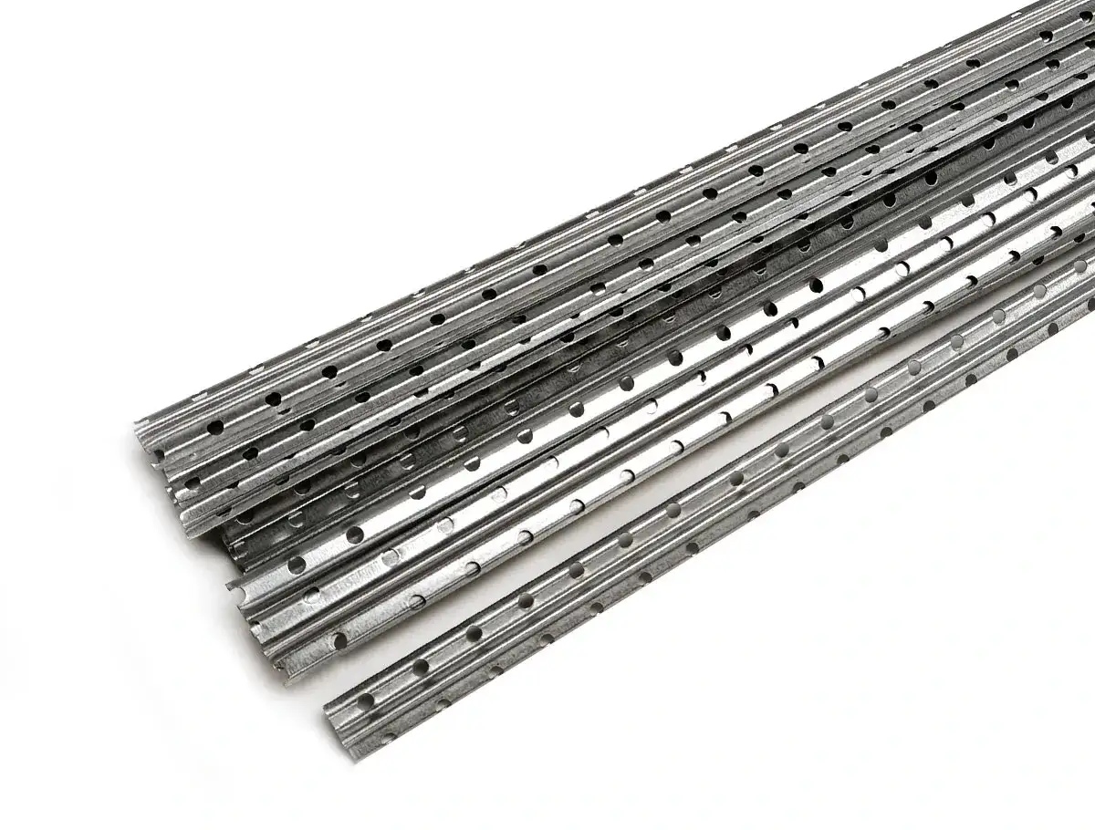 Metalowe listwy prowadzące do tynków, z licznymi otworami, ułożone w stos.