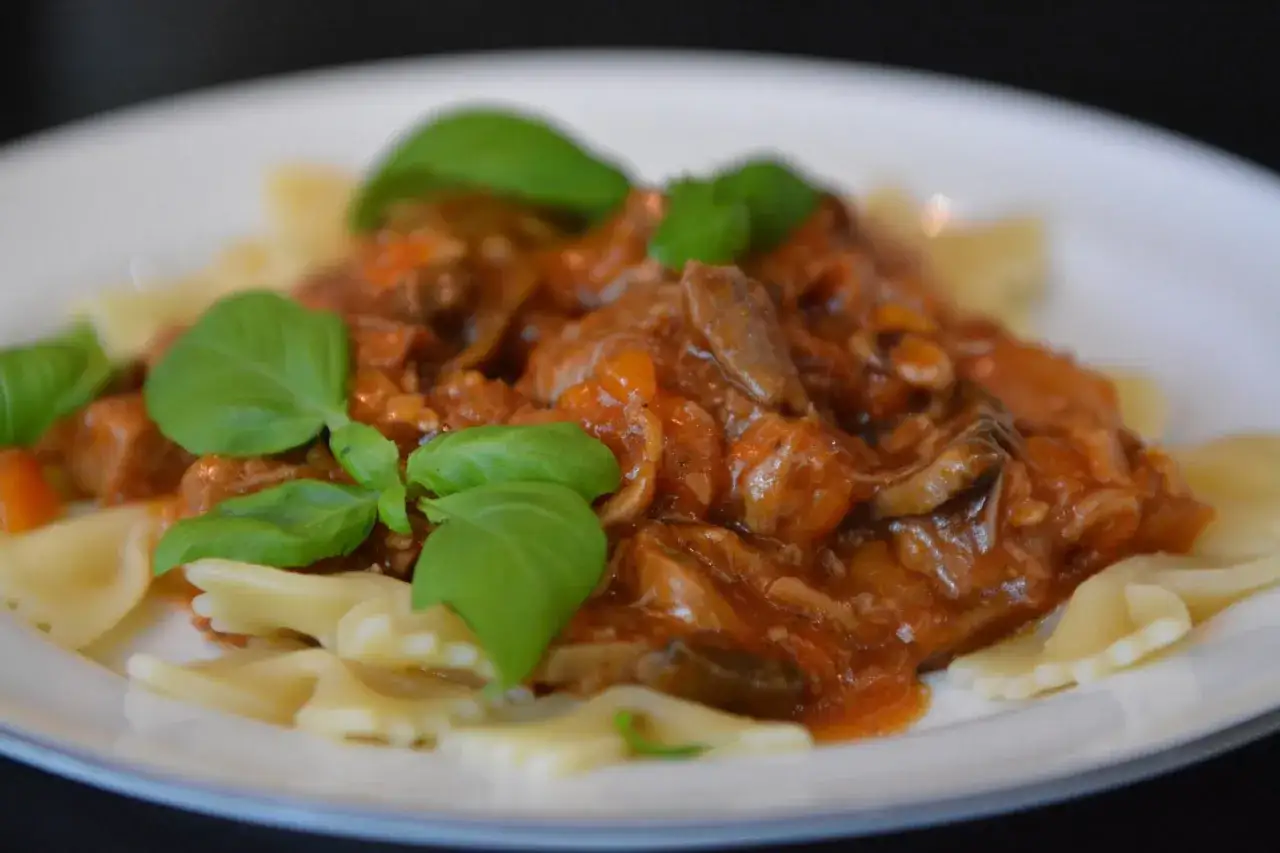 Pyszny gulasz z łopatki wieprzowej z pieczarkami i pomidorami, podany z makaronem farfalle. Idealny pomysł, co zrobić z łopatki na obiad.