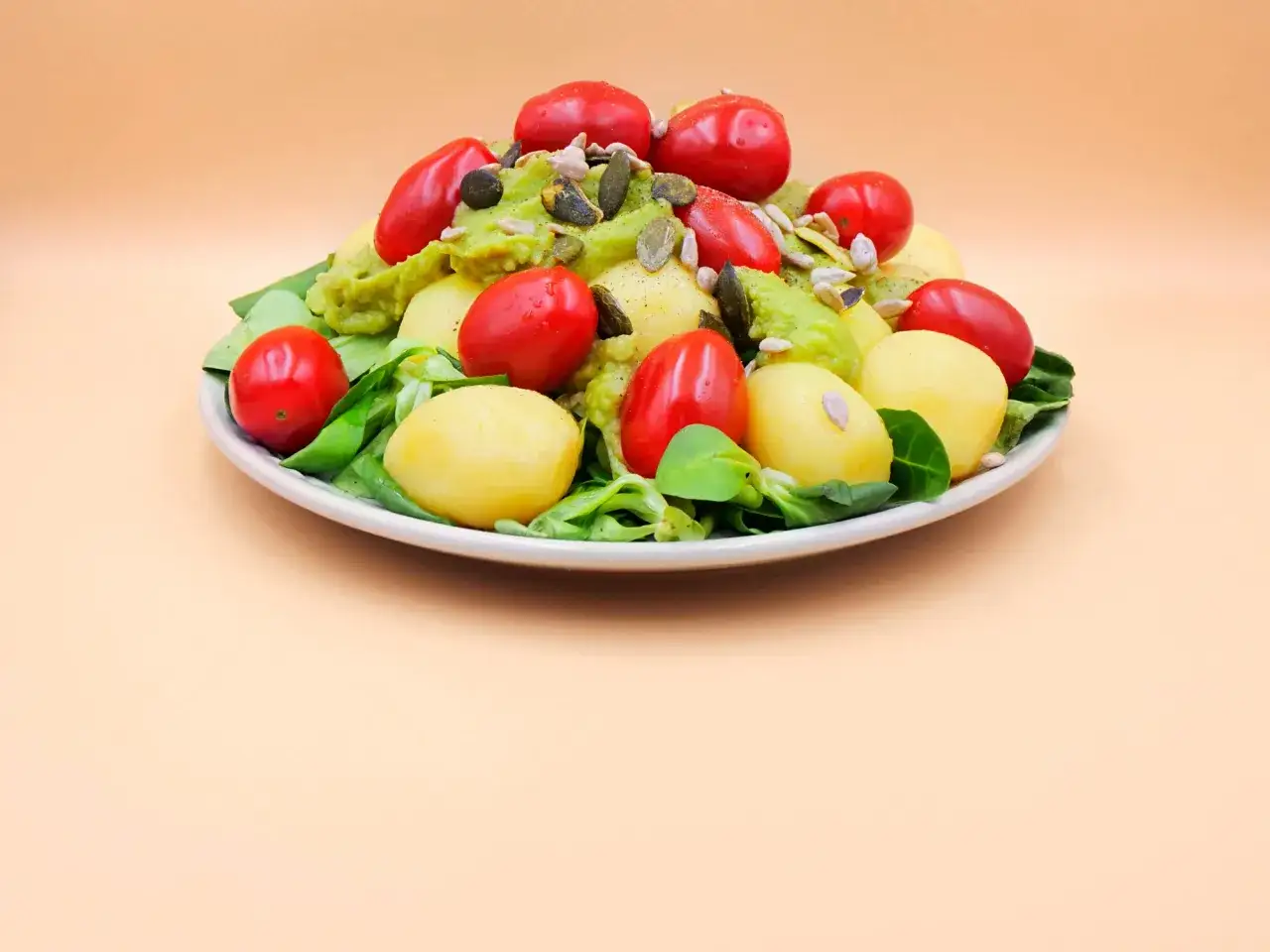 Sałatka z ziemniakami, pomidorkami i guacamole. Jak jeść to pyszne danie? Z dodatkiem pestek dyni i słonecznika.