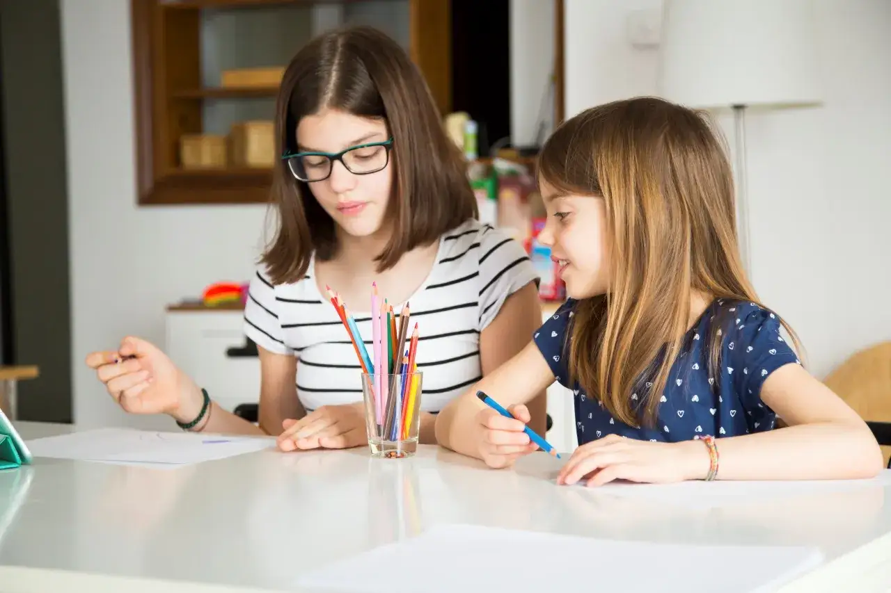 Dwie dziewczynki uczą się rysować, co może być początkiem edukacji domowej. Jak zacząć? Od wsp&oacute;lnego rysowania!