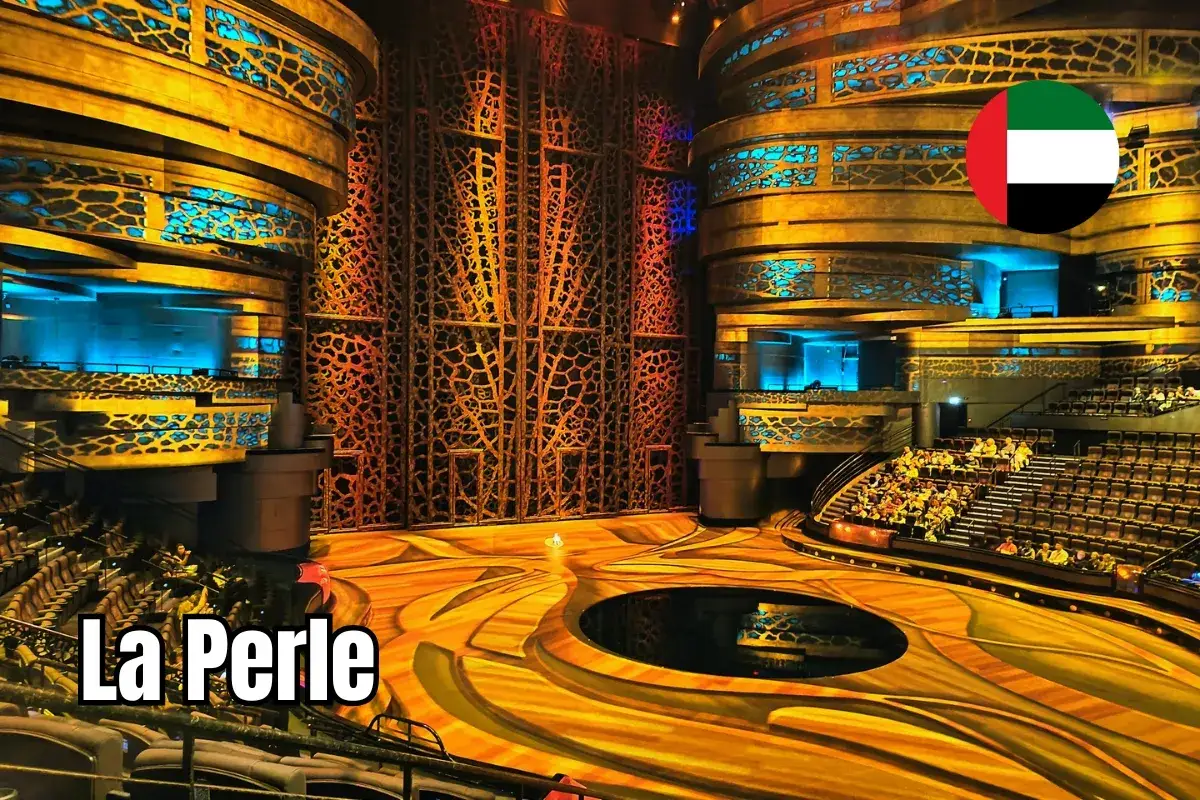 Wnętrze teatru La Perle w Dubaju, z widownią i sceną w złotych barwach, ozdobione niebieskimi światłami.