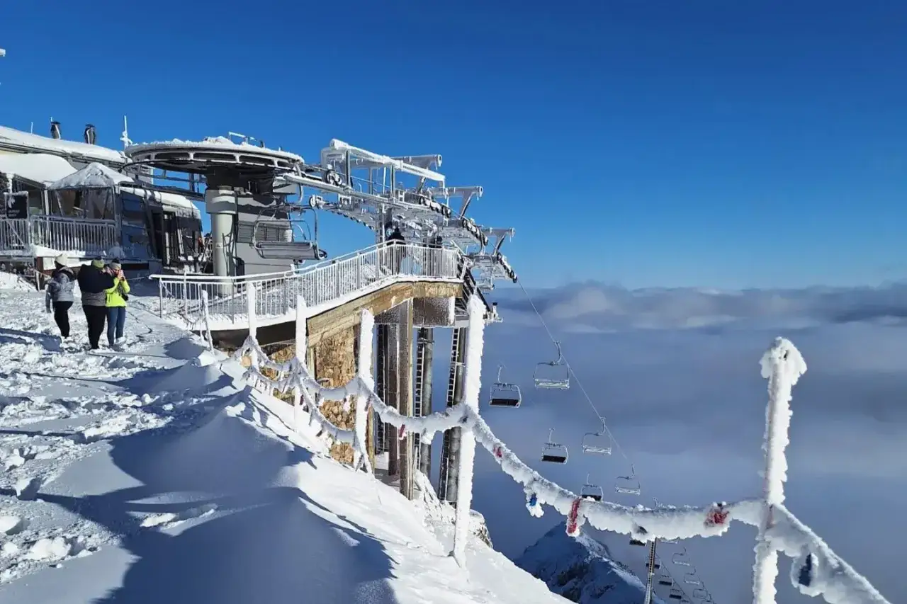 Zimowy krajobraz na Kasprowym Wierchu. Kolejka linowa zawieszona nad morzem chmur, a śnieg pokrywa wszystko wok&oacute;ł.