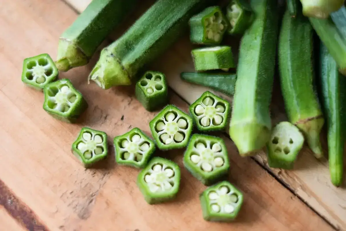 Pokrojona okra po polsku, z widocznymi nasionami w przekroju, ułożona na drewnianym blacie.