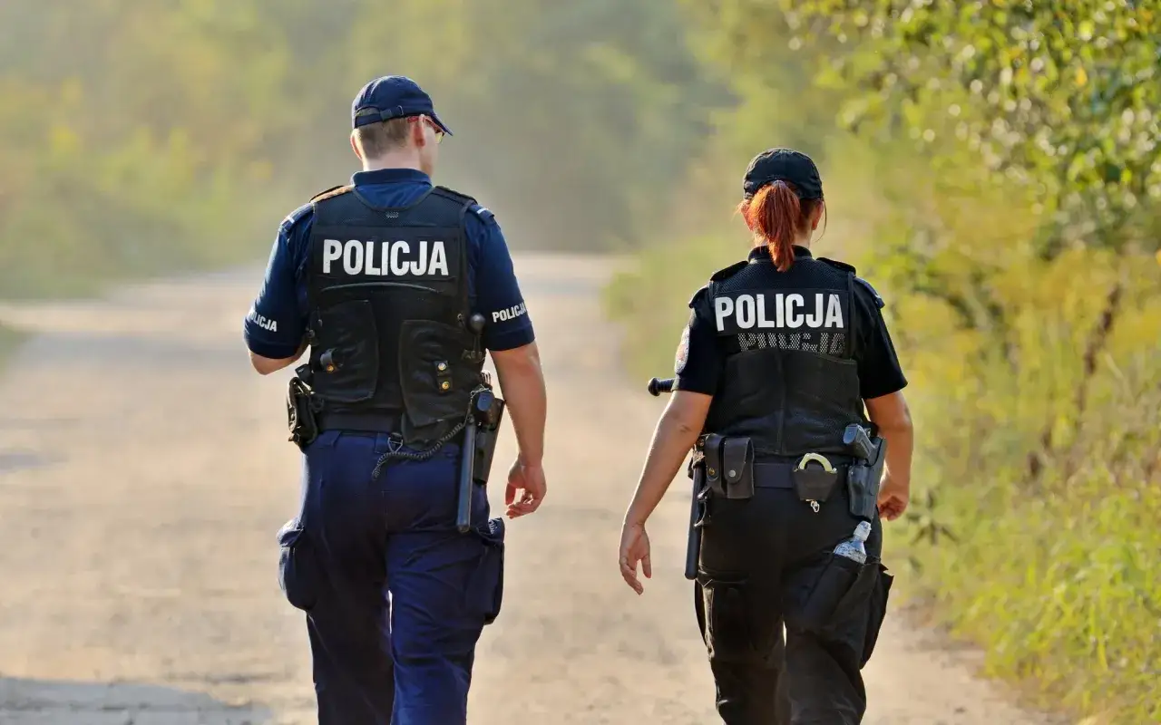 Policjanci w pełnym umundurowaniu, zgodnie z rozporządzeniem w sprawie umundurowania policjantów, patrolują teren.