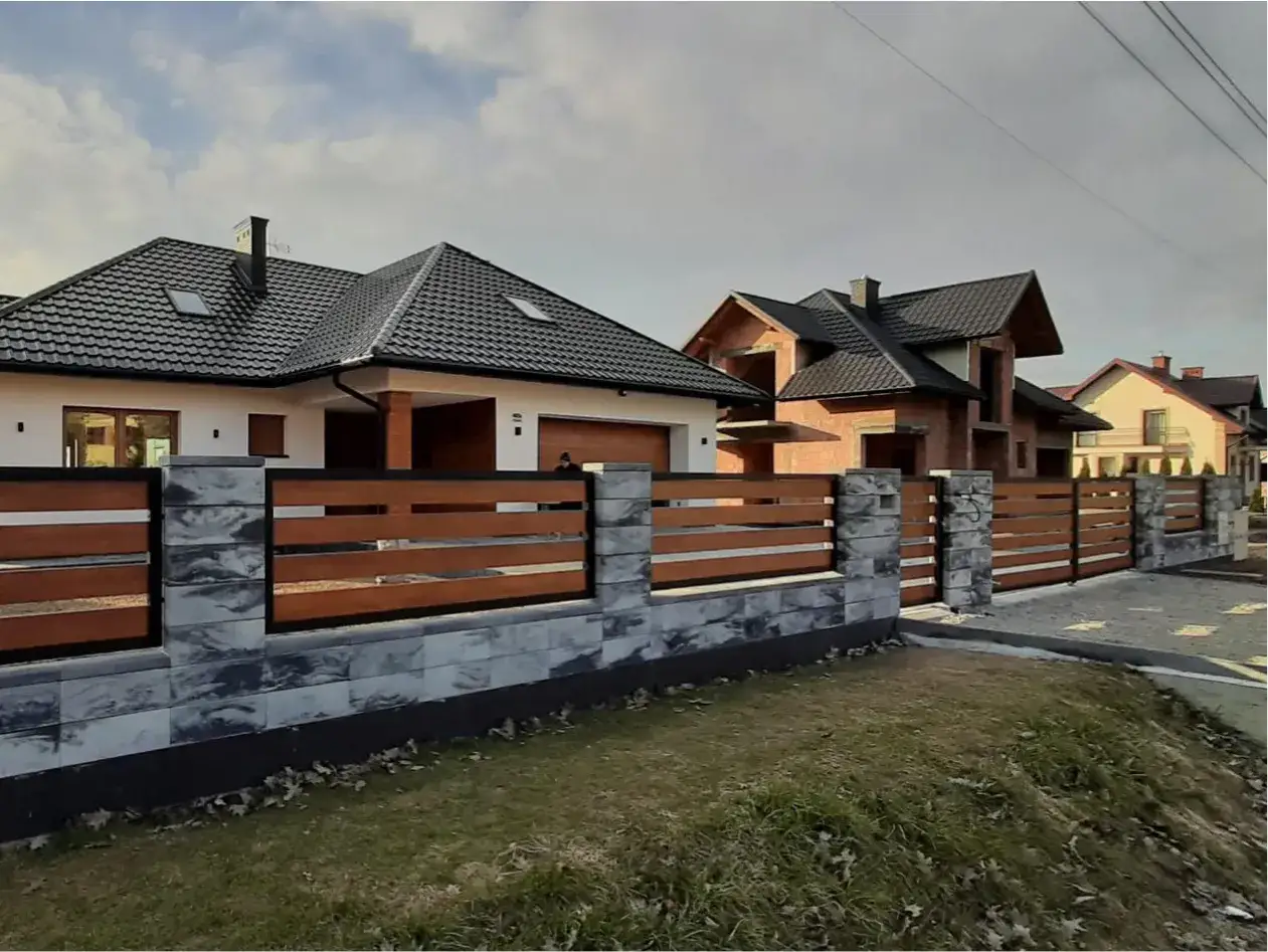 Nowoczesne ogrodzenia z kamienia i drewna, tworzące ciekawe ogrodzenia galeria. Domy w tle.