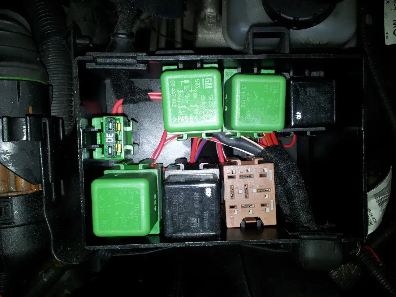 W skrzynce bezpieczników widać zielone przekaźniki, w tym jeden oznaczony jako przekaźnik świec żarowych.