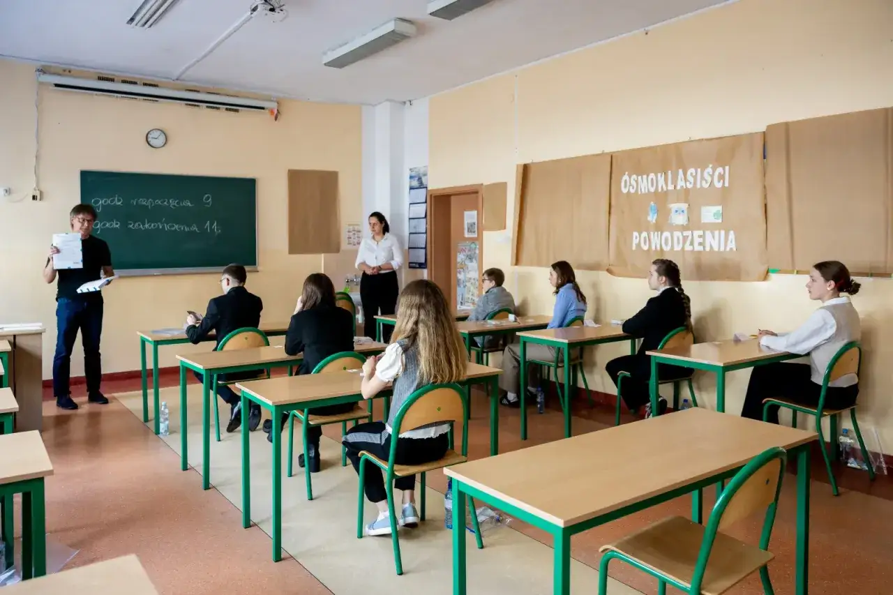 Uczniowie ósmoklasiści siedzą w ławkach, przygotowując się do egzaminu. To ważny moment, co jest po podstawówce.