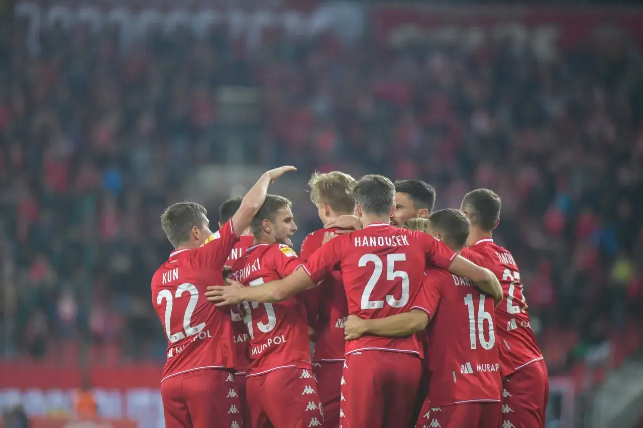 Piłkarze w czerwonych strojach świętują, być może unikając spadku z ekstraklasy.