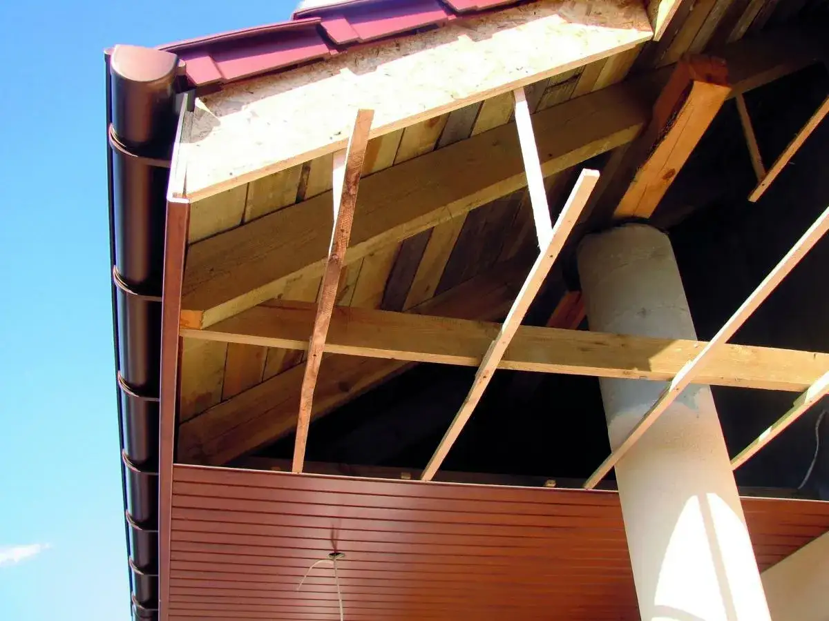 Trwa montaż podbitki pcv. Widoczna konstrukcja dachu, rynna i komin.