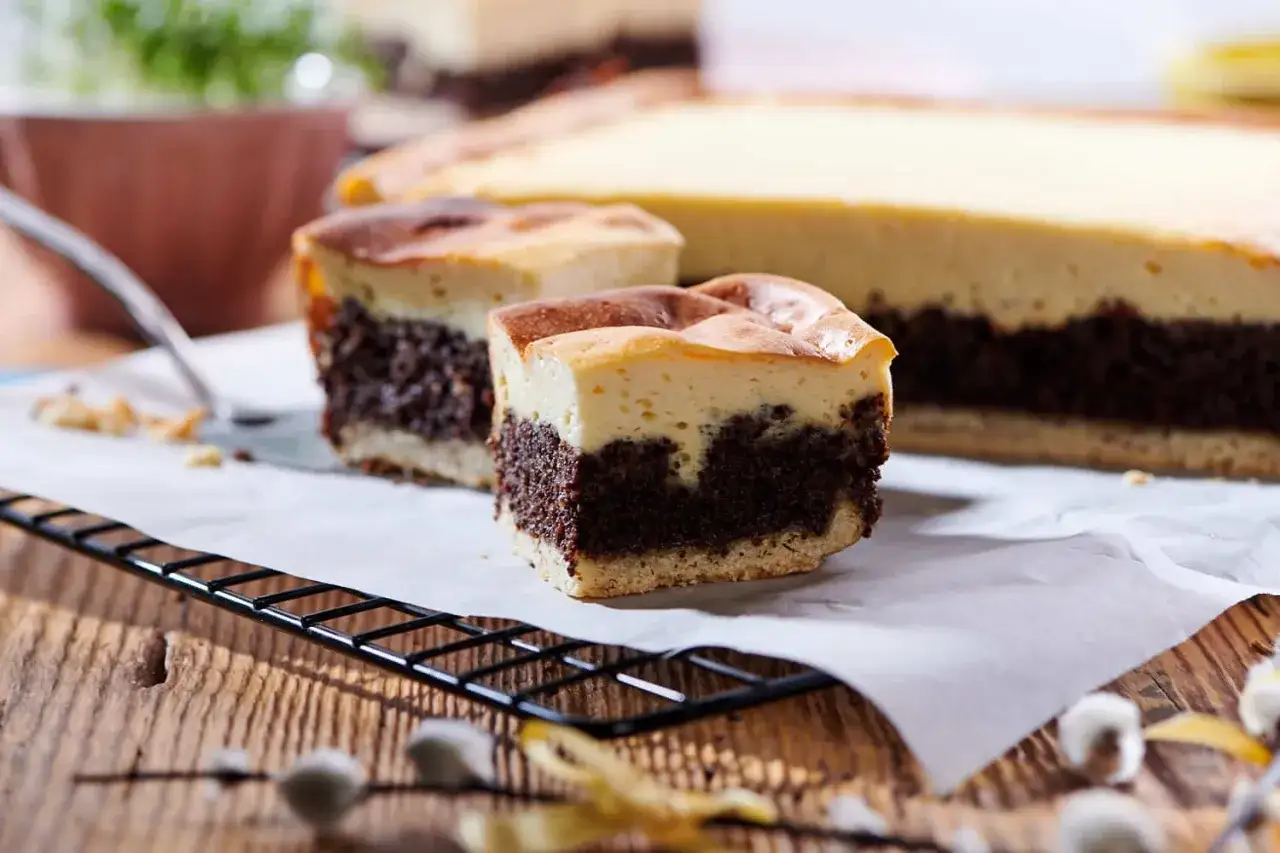 Pyszny sernik z makiem, z dwoma kawałkami na wierzchu, prezentuje się apetycznie na drewnianym stole.