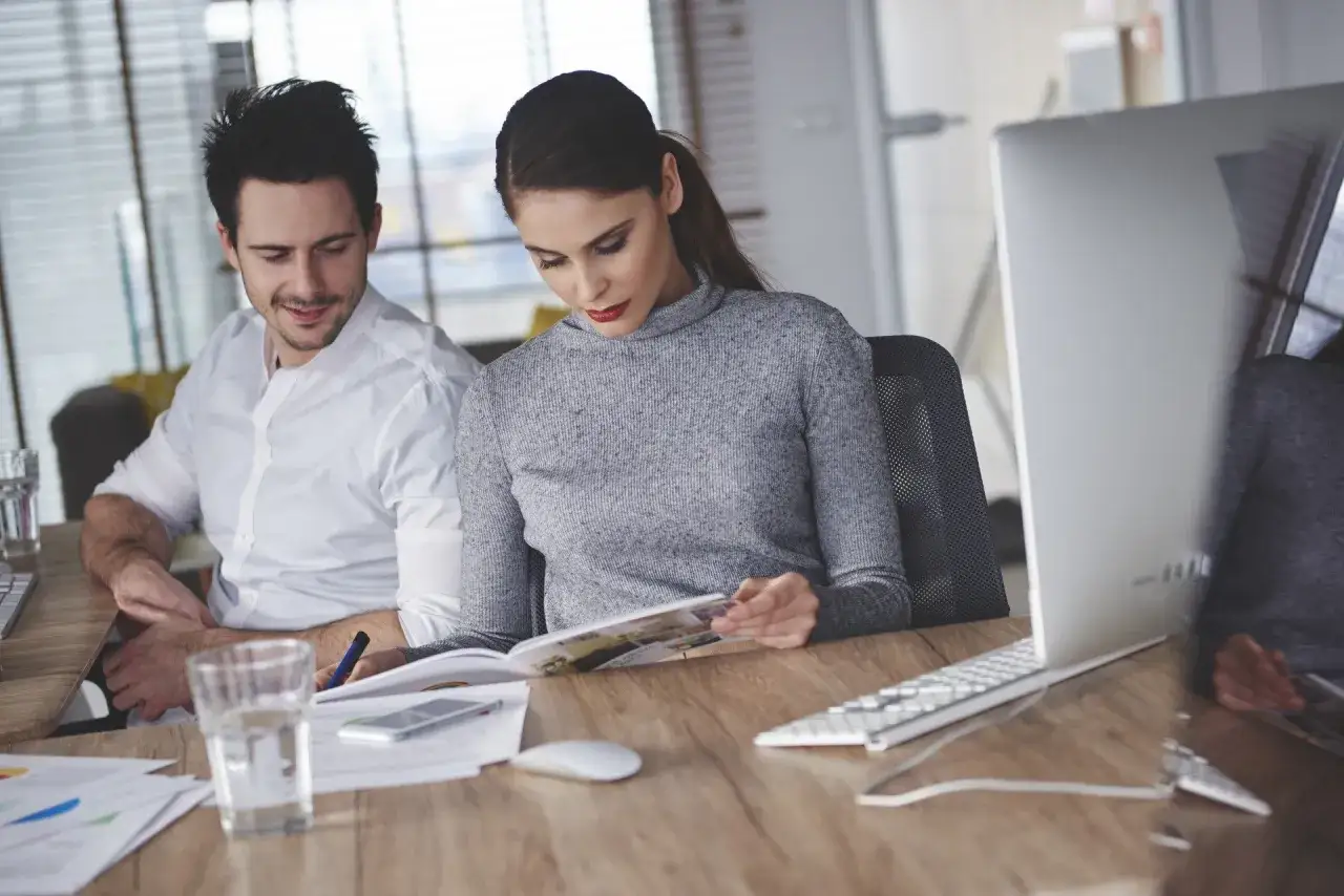 Mężczyzna wpatruje się w kobietę przy biurku, być może to zakochany szef objawy jego zauroczenia są widoczne.