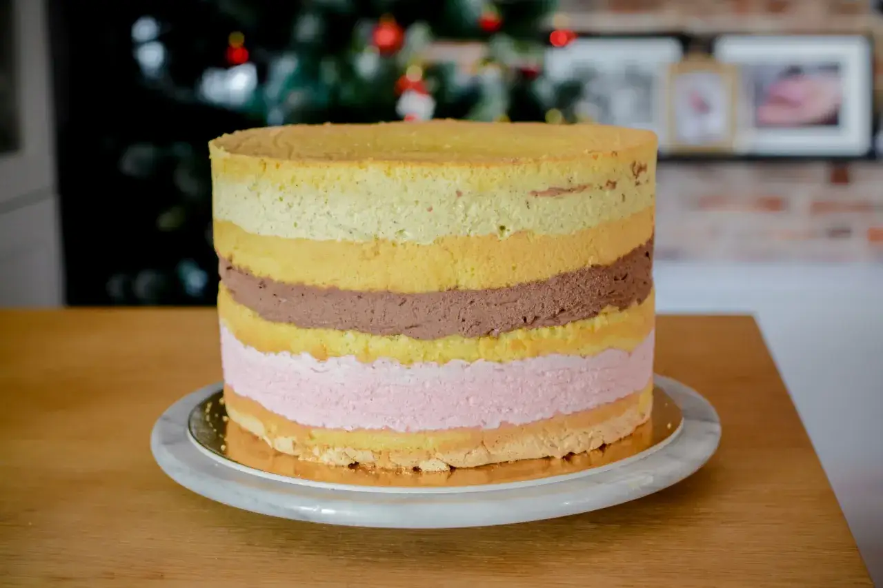 Przekrój tortu z różnymi warstwami kremu, frużeliny i chrupiącej wkładki