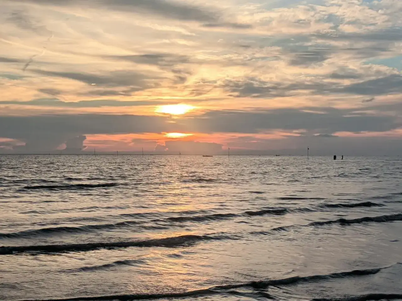 Zachód słońca nad spokojnym morzem, idealne miejsce, gdzie warto pojechać nad morze. Delikatne fale i ciepłe barwy nieba tworzą magiczny klimat.