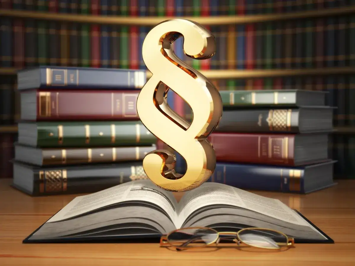 Złoty paragraf na tle książek prawniczych symbolizuje konsekwencje, co grozi za groźby karalne.