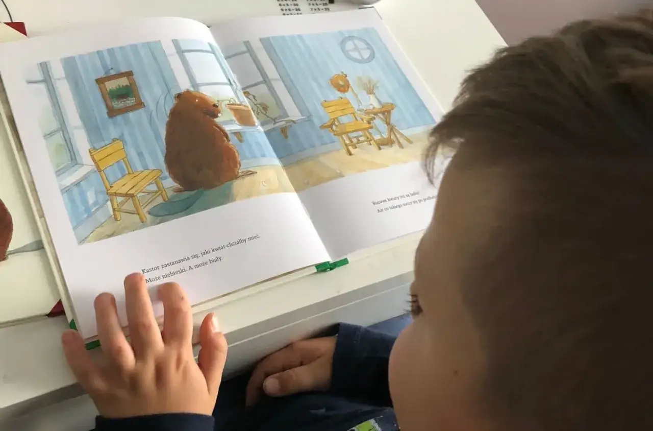 Dziecko uczy się w domu, uśmiechnięte, z książkami