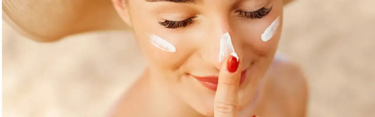 kobieta nakładająca krem z filtrem SPF 50 na twarz