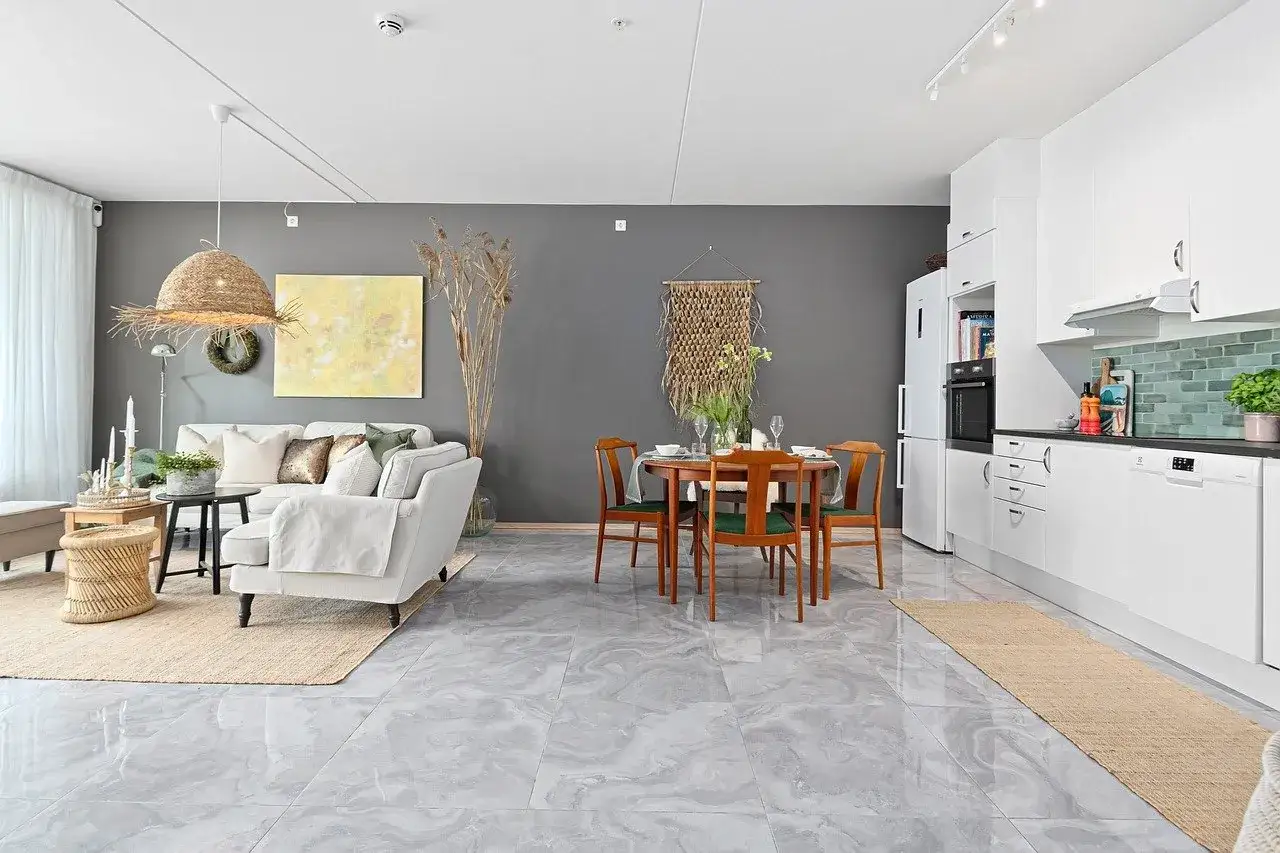 Nowoczesny salon z jadalnią i kuchnią. Zastanawiasz się, jak często malować ściany? W tym wnętrzu szare ściany dodają elegancji.
