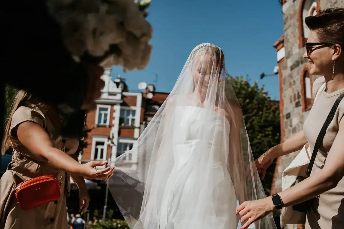 Panna młoda w welonie, obok niej dwie kobiety. Czy warto wynająć wedding plannera, czy poradzić sobie samemu?