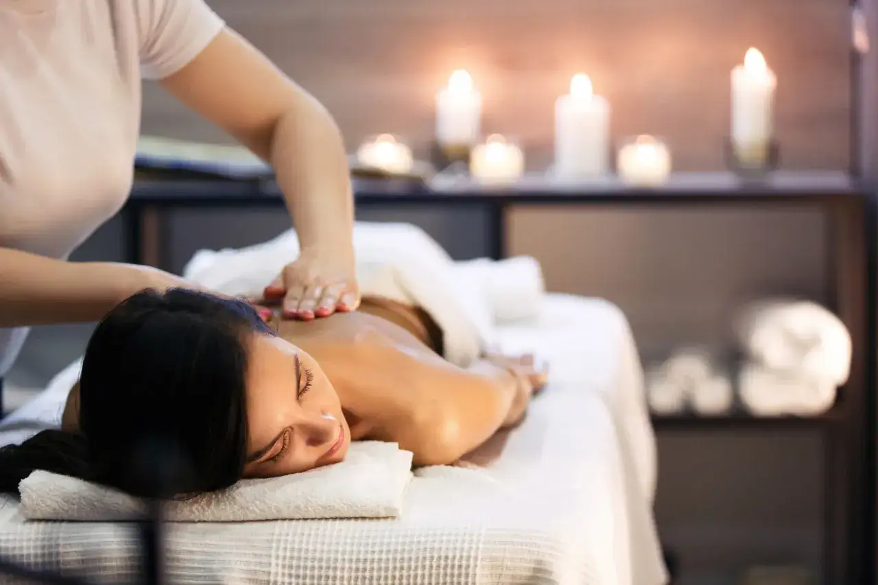 Relaksacyjny masaż pleców w spa w Rudzie Śląskiej. Kobieta odpoczywa przy blasku świec.