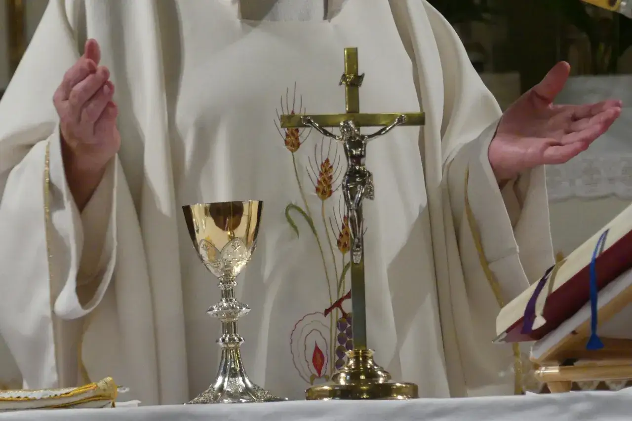 Msza wieczorna przed świętem. Kapłan w białej szacie z krzyżem i kielichem, przygotowuje się do liturgii.
