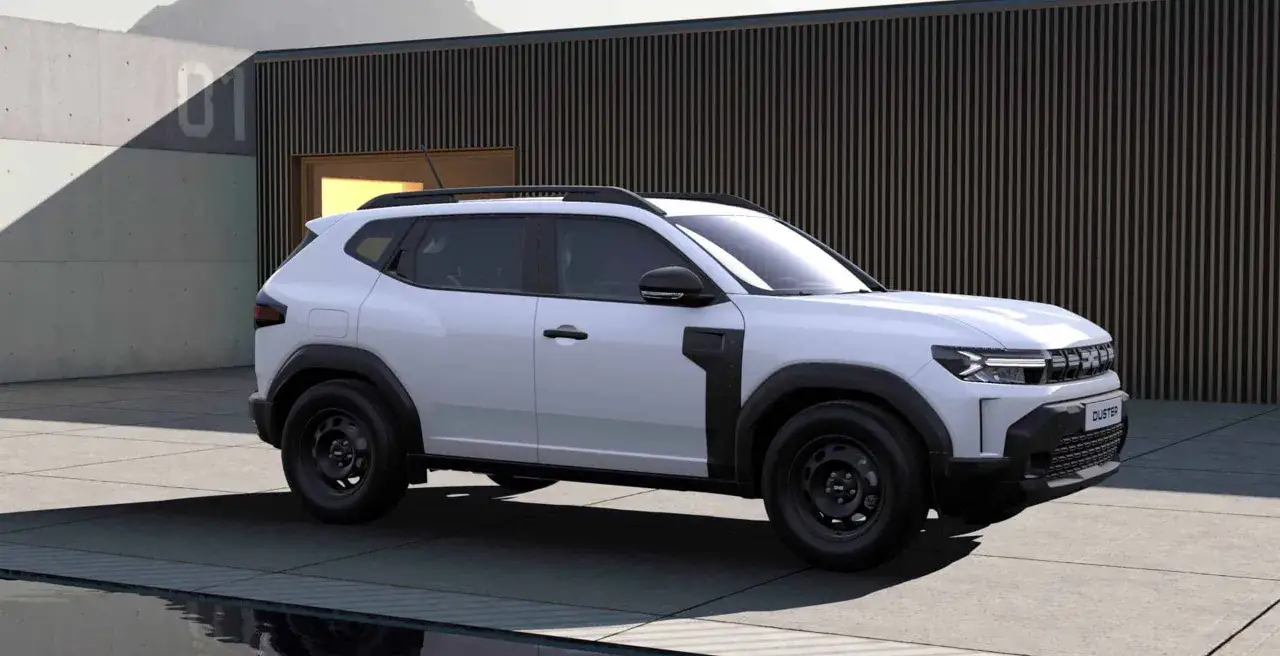 Nowa, biała Dacia Duster z czarnymi dodatkami, zaparkowana przed nowoczesnym budynkiem.